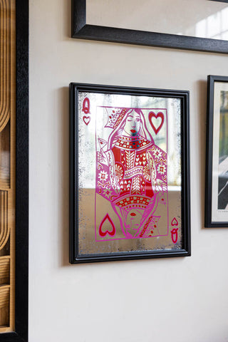 The Queen Of Hearts Decorative Playing Card Mirror displayed on a wall amongst some art prints.