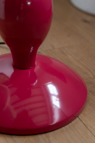 Close-up of the base of the Raspberry Red Wavy Retro Floor Light, displayed on a wooden floor.