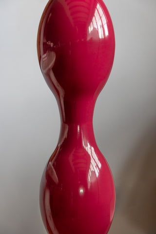 Close-up of the Raspberry Red Wavy Retro Floor Light in front of a white wall.