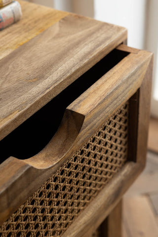 Close-up of a rattan bedside table with the top drawer open.