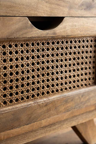 Close-up of the front of a drawer on a rattan bedside table.