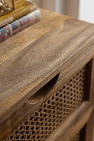 Close-up of the surface of a rattan bedside table, styled with books and a small box on.