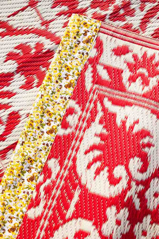 Red and white reversible plastic rug with floral detailing for outdoor spaces.