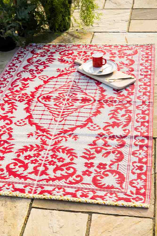 Weatherproof outdoor rug in a reversible red and white floral design.