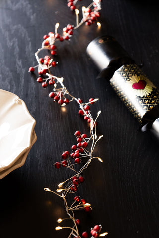 The red berry light chain snaking down the centre of a table.