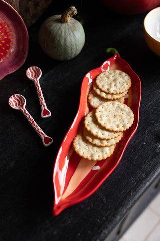 Red chilli serving plate with crackers on a dark autumn styled table