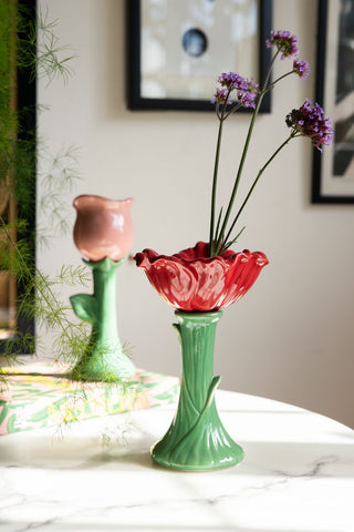 The Red Flower Earthenware Single Stem Vase styled with greenery inside, on a white marble surface with another vase and home accessories.