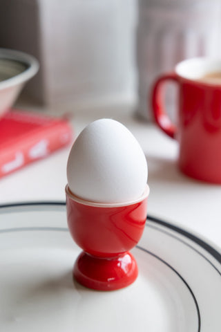 A red egg cup with a white egg in it 