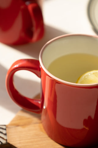 Close-up of a red ceramic mug filled with hot water and lemon  