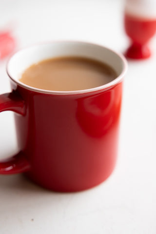 Close-up of a red mug with white rim, filled with tea