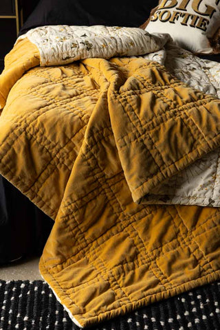 Close-up of the Reversible Gold Rock & Rose Throw draped across a bed.