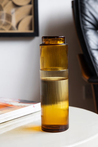 The Ribbed Amber Glass Carafe styled on a table with the matching tumbler together