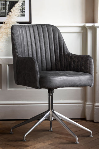 The Ribbed Antique-Style Black Leather Swivel Chair styled in front of a white panelled wall.