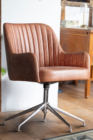 The Ribbed Antique-Style Brown Leather Swivel Chair in front of a white wall, with furniture and accessories in the background.