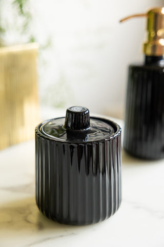 The Ribbed Black Glass Storage Canister styled with the matching soap dispenser in the background.