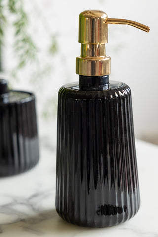 Close-up of the Ribbed Black Glass & Gold Effect Soap Dispenser on a white marble surface.