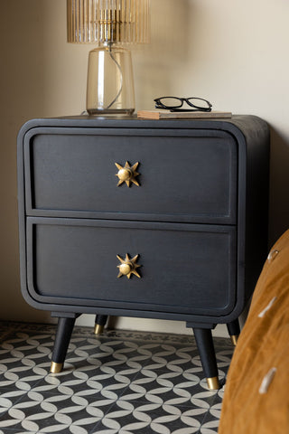 The Ringo Bedside Table on a geometric floor next to a bed, with a table lamp, book and some glasses styled on the top.