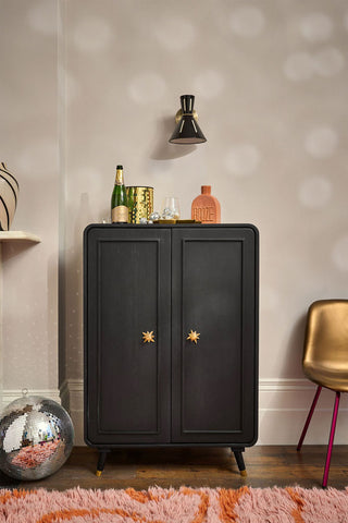 The Ringo Drinks Cabinet styled with various bar accessories on top, next to a chair, disco ball and a rug.