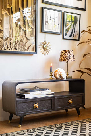 The Ringo TV Unit seen from an angle, styled in front of a wall with art prints and with various home accessories.