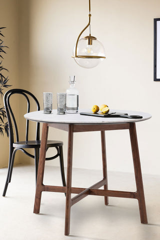 The Round Acacia & Marble Dining Table styled with various kitchen accessories on, with a dining chair, ceiling light, plant and art print.