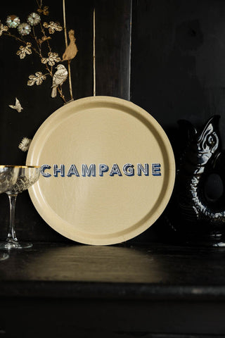 The Round Champagne Tray displayed on a black sidebaord with a jug and cocktail glass, leaning against the wall.