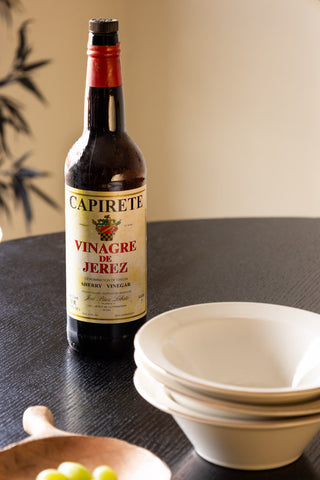 The Round Dining Table styled with a glass bottle, bowls and serving dish on.