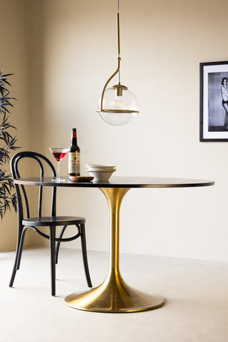 The Round Dining Table styled with various tableware, a pendant light, plant and art print.