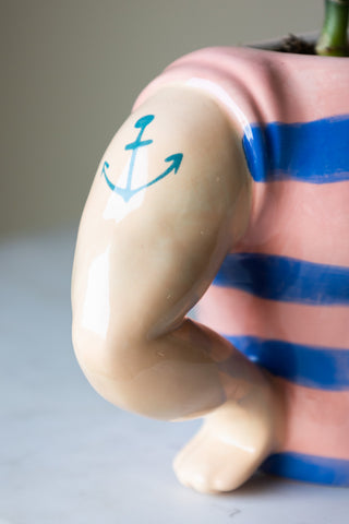 Unique sailor-inspired ceramic storage pot with a bold design and sculpted arms with an anchor tattoo in blue.