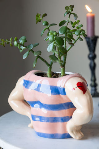 Quirky sailor-inspired ceramic planter with bold stripes and sculpted arms, styled with a succulent on a marble table.