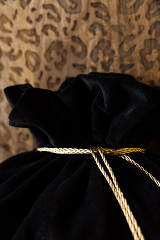 Close-up of the top and the cord tie on the Santa I Can Explain Velvet Christmas Sack, displayed in front of a wooden leopard print unit.