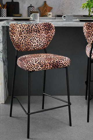 The Set Of 2 Bar Stools in Leopard Print Velvet displayed in a kitchen with a breakfast bar in the background.