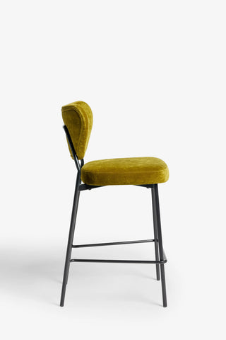 One of the Set Of 2 Bar Stools in Needlecord Velvet Green seen from the side, in front of a white background.