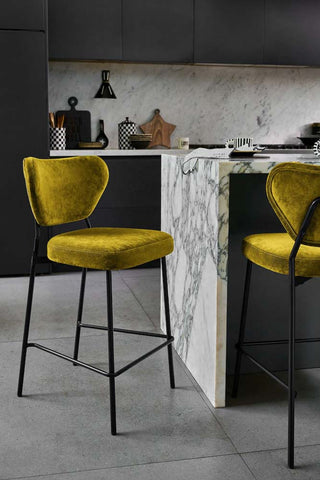 Two green velvet bar stools styled in a kitchen.