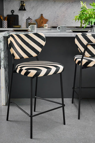 The Set Of 2 Bar Stools in Stripe Velvet styled in a kitchen with a kitchen island in the background.