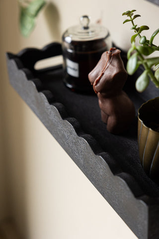 Close-up of the Set Of 2 Black Wooden Scalloped Wall Shelves, styled with a candle, book and plant