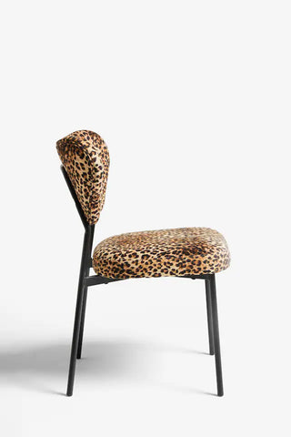 A leopard print dining chair seen from the side, on a plain background.