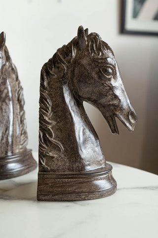 Close-up of one of the Set Of 2 Horse Head Bookends on a white marble table, with the other bookend in the background.