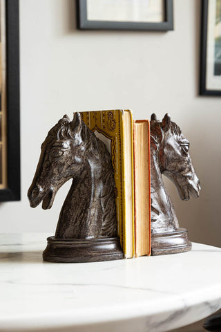 The Set Of 2 Horse Head Bookends on a white table with some books styled in the middle.