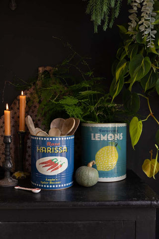 A wide lifestyle image of The Set Of 2 Lemon & Harissa Storage Tins - Large displayed on a black sideboard, styled with autumnal kitchen accessories