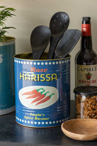 Close-up of one of the Set Of 2 Lemon & Harissa Storage Tins - Large with utensils inside, with the other in the background and various kitchen accessories also in the shot.