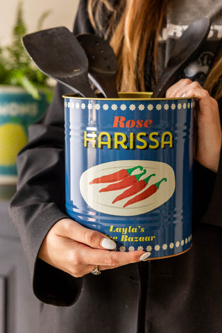 The Harissa Storage Tin being held with utensils inside.