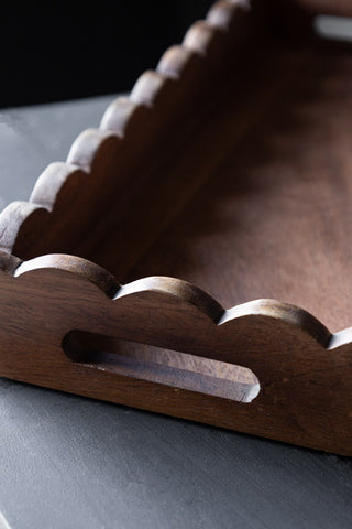 Close-up of one of the Set Of 2 Natural Wooden Scalloped Wall Shelves on a dark surface.