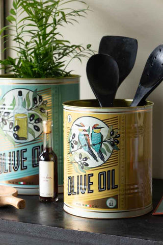 The Set Of 2 Olive Oil Storage Tins - Large styled on a black sideboard with a plant and kitchen accessories.