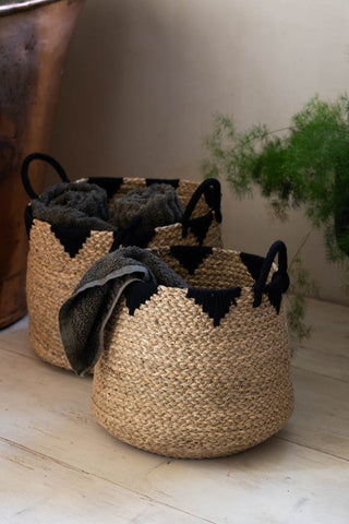 The Set Of 2 Seagrass Baskets styled on wooden floor next to a copper bath and plant, with towels inside.