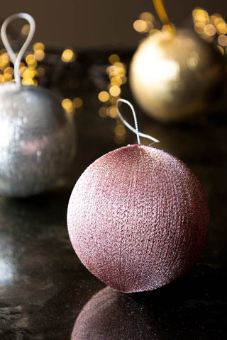 The Set Of 3 Metallic Spun Thread Christmas Bauble Decorations styled on a dark marble surface with fairy lights.