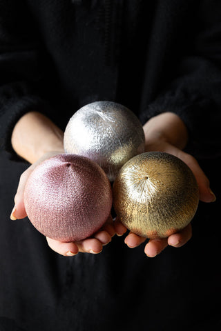 The Set Of 3 Metallic Spun Thread Christmas Bauble Decorations being held in a model's hands.