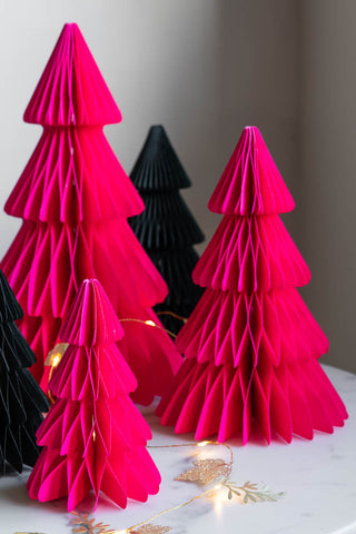 The Set Of 3 Neon Pink Paper Trees styled on a white surface with fairy lights and other green trees