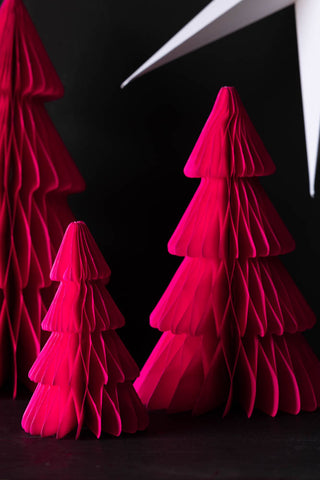 The Set Of 3 Neon Pink Paper Trees styled on a dark surface with a white star decoration in the background.