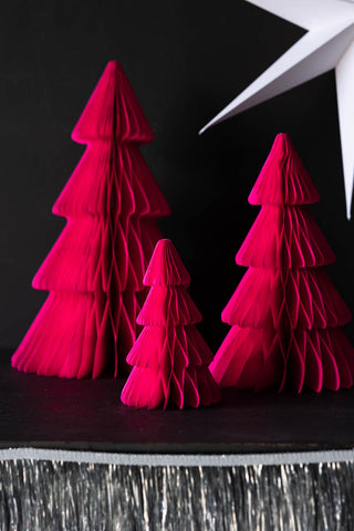 The Set Of 3 Neon Pink Paper Trees styled on a dark surface with a silver tinsel garland and a white star decoration.