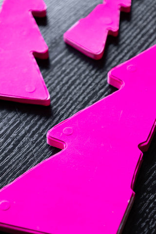 The Set Of 3 Neon Pink Paper Trees unassembled, displayed on a dark wooden surface.